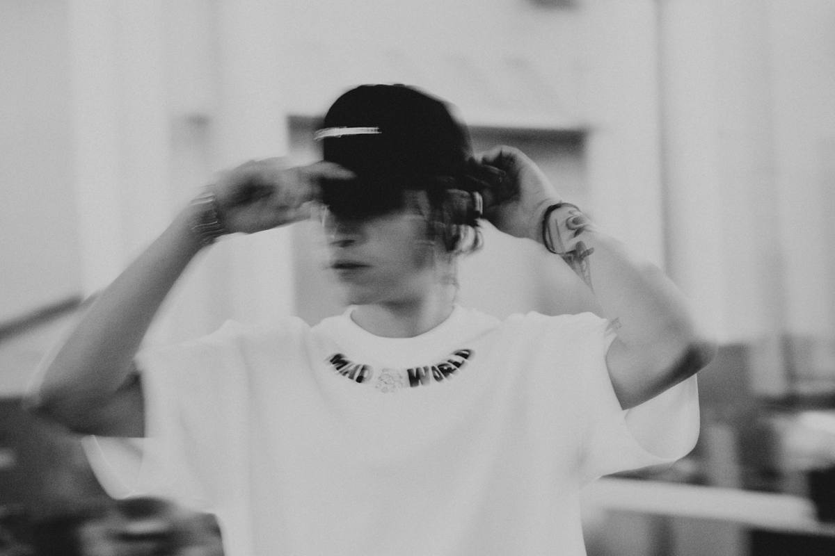Person in a plain white tee adjusting a cap