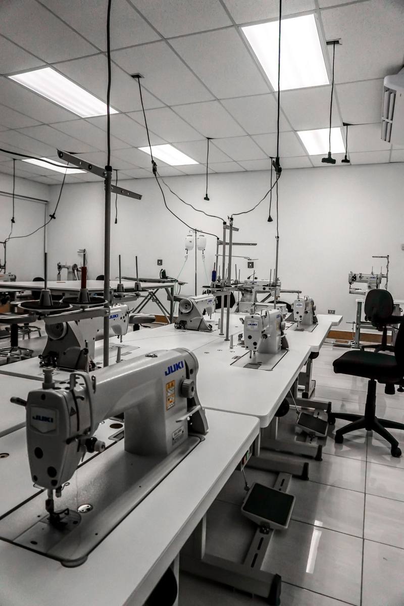 Rows of industrial sewing machines in an empty workroom